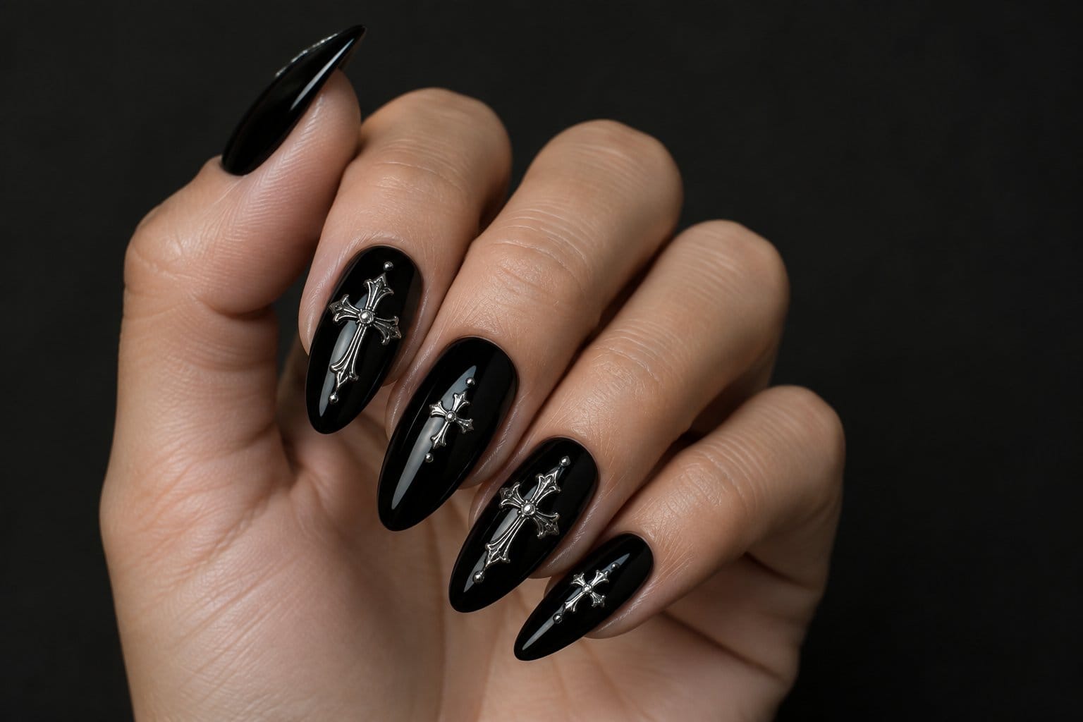 A hand with black nails decorated with silver crosses.