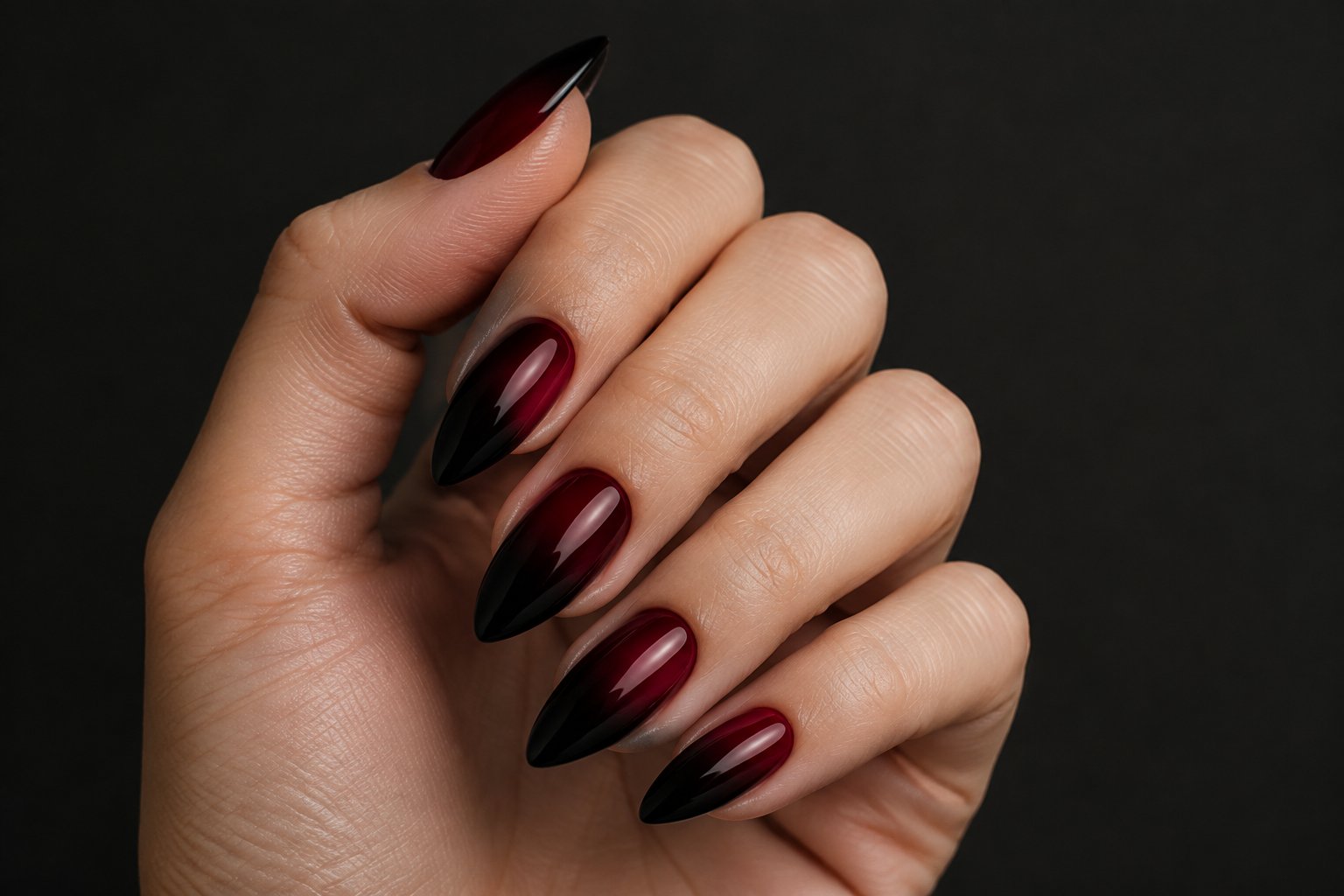 A hand displaying burgundy-to-black ombré nails.