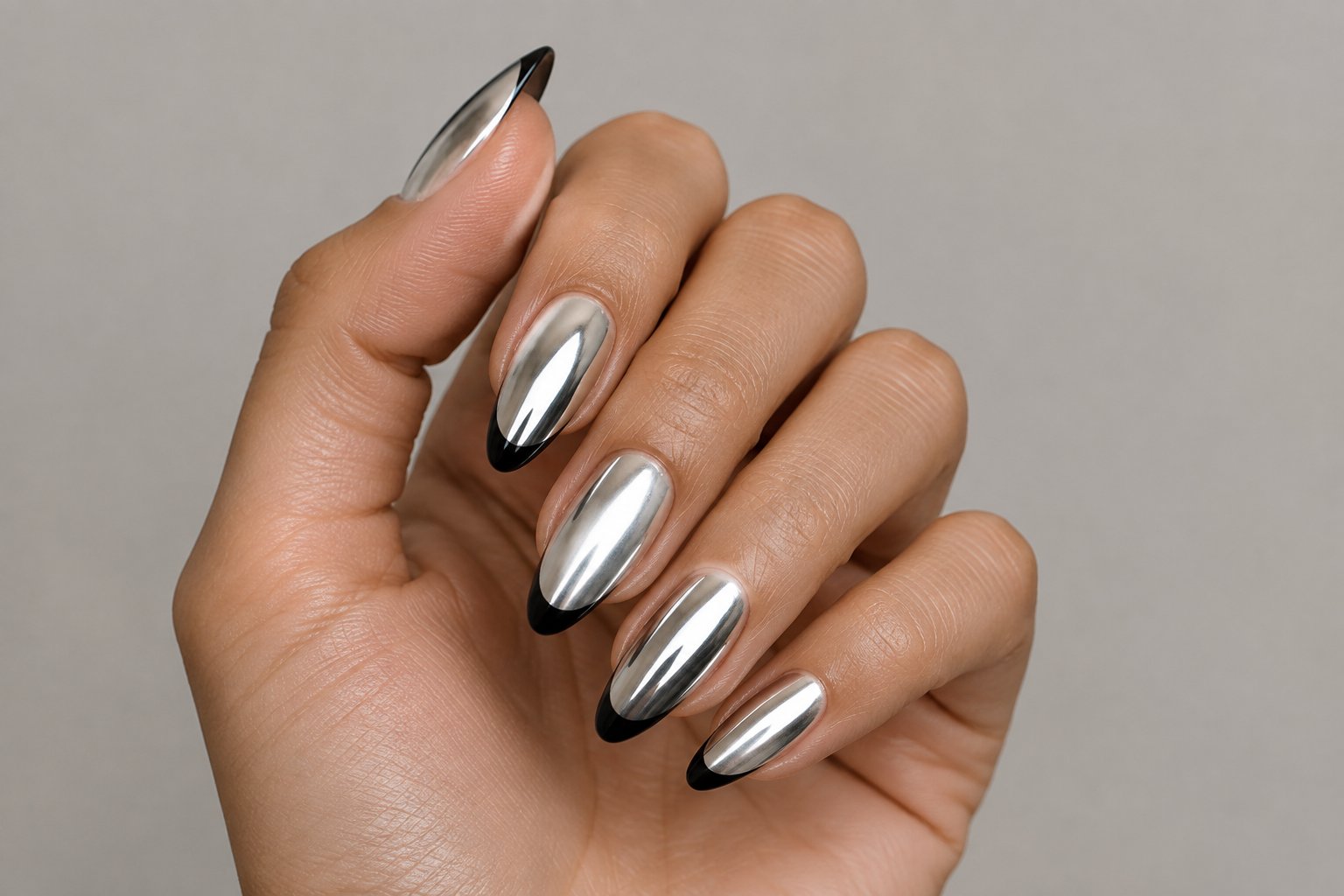 A hand displaying silver nails with black tips.