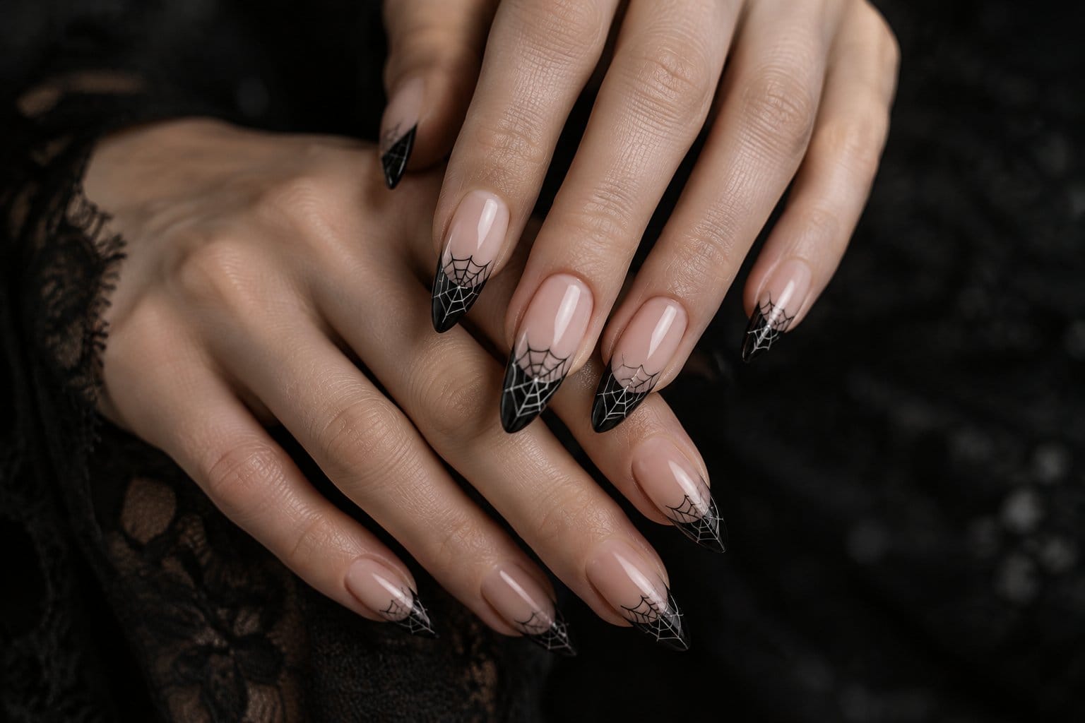 A pair of hands displaying black-tipped nails with delicate web designs.