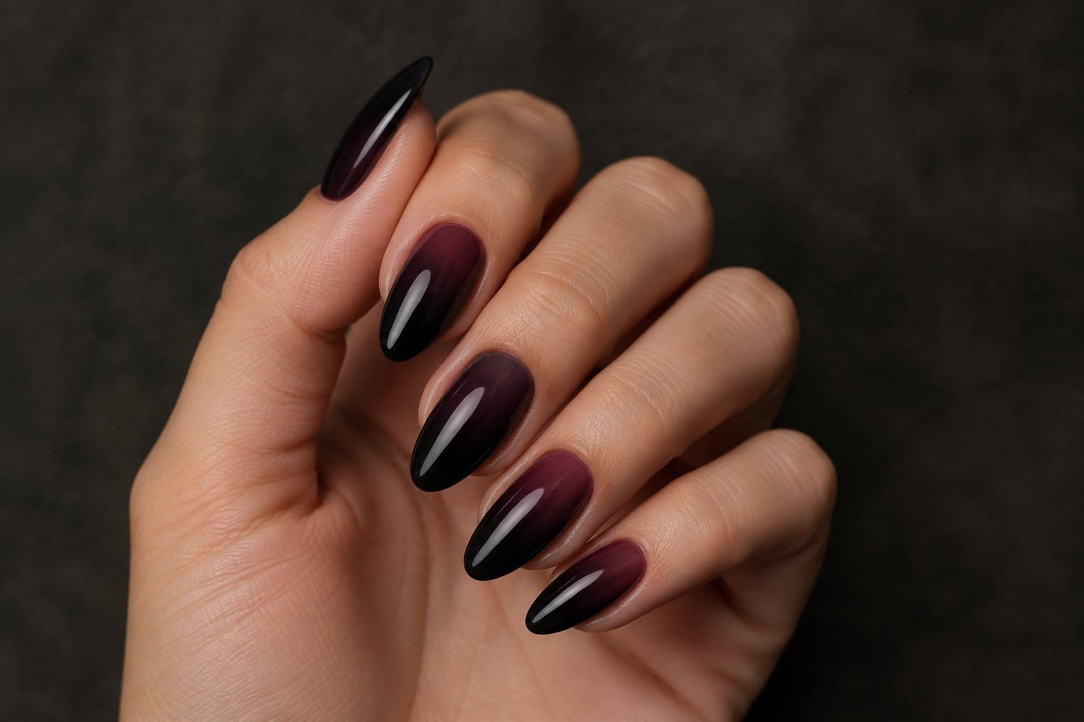 A hand displaying black-to-plum ombré nails.