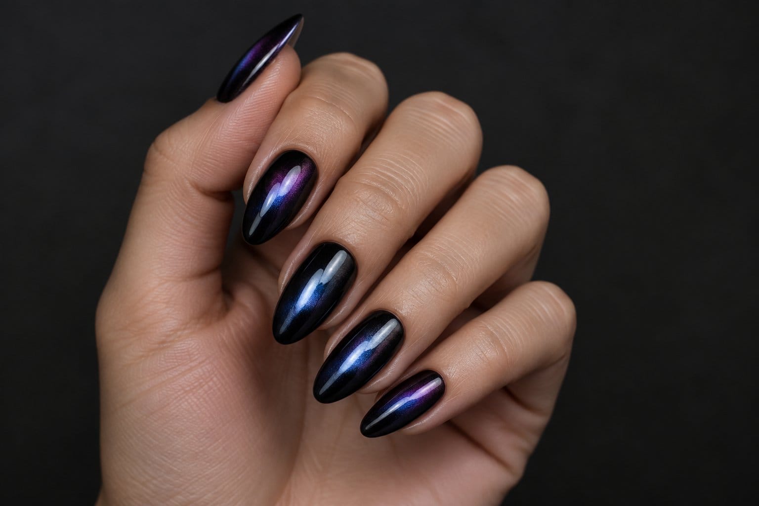 A hand displays long, glossy black almond-shaped nails.
