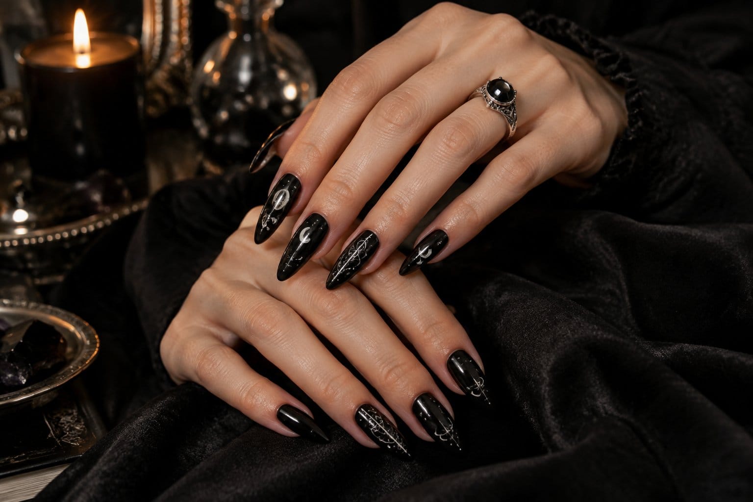 A woman displays glossy black nails with small silver moon and star designs.